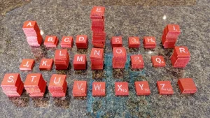 Lettres de Scrabble en français empilées, dont le Q à 8 points, pour trouver un mot avec Q
