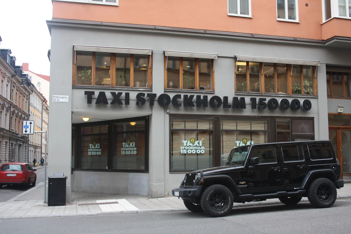 Taxi jaune devant un bâtiment, TAXI est un mot avec X au milieu