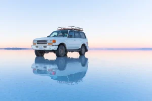 Salar d’Uyuni en Bolivie, reflet d’un 4x4 sur le désert de sel inondé, pays en B