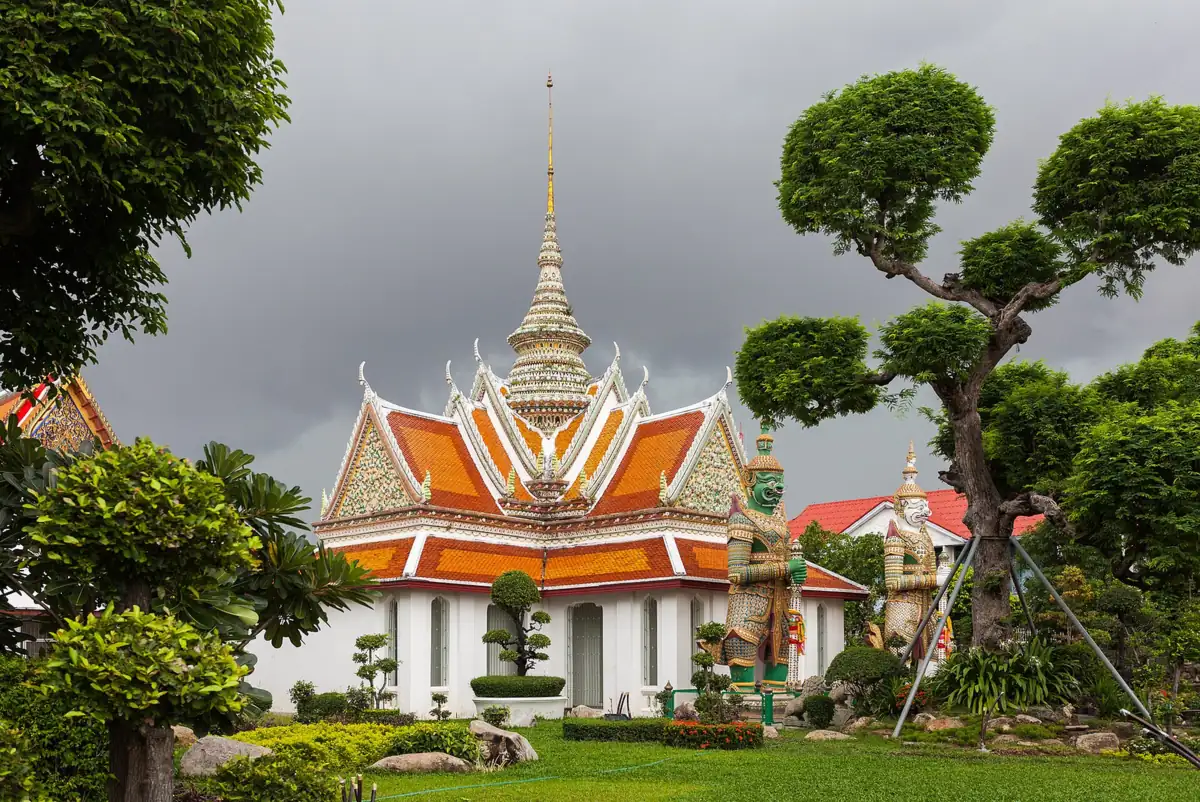 Pavillon aux toits orange et blancs du temple Wat Arun gardé par deux statues de géants, à Bangkok, en Thaïlande, pays en T